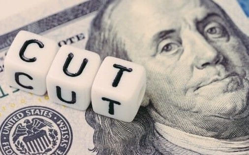 dice forming the word 'cut' atop a $100 bill